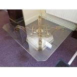A beige and grey marble square coffee table with cast iron cross support on square glass top.