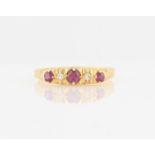 A hallmarked 18ct yellow gold ruby and diamond five stone ring, set with three round cut rubies