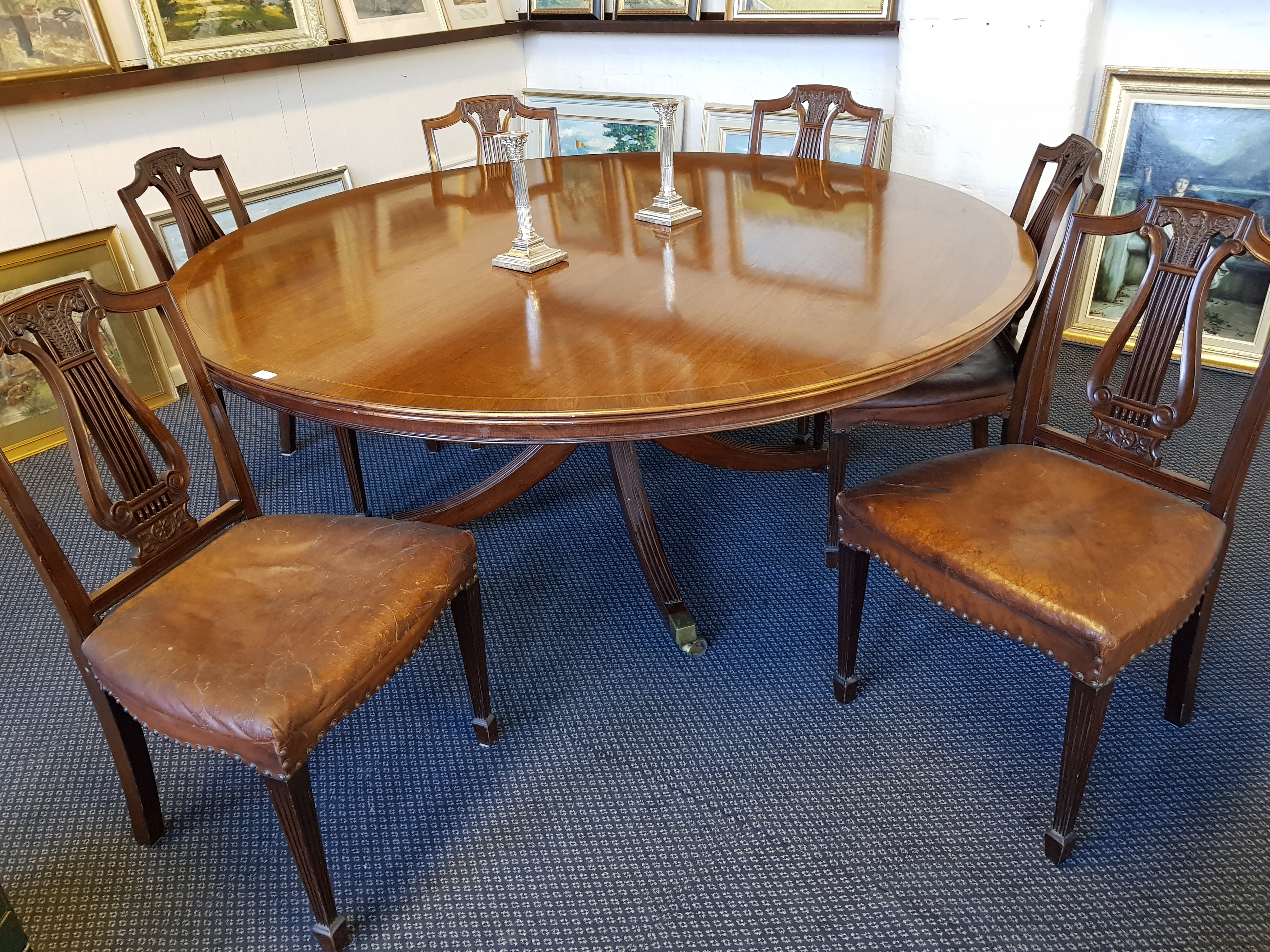 A large reproduction circular mahogany dining table on circular base and six lyre back chairs.