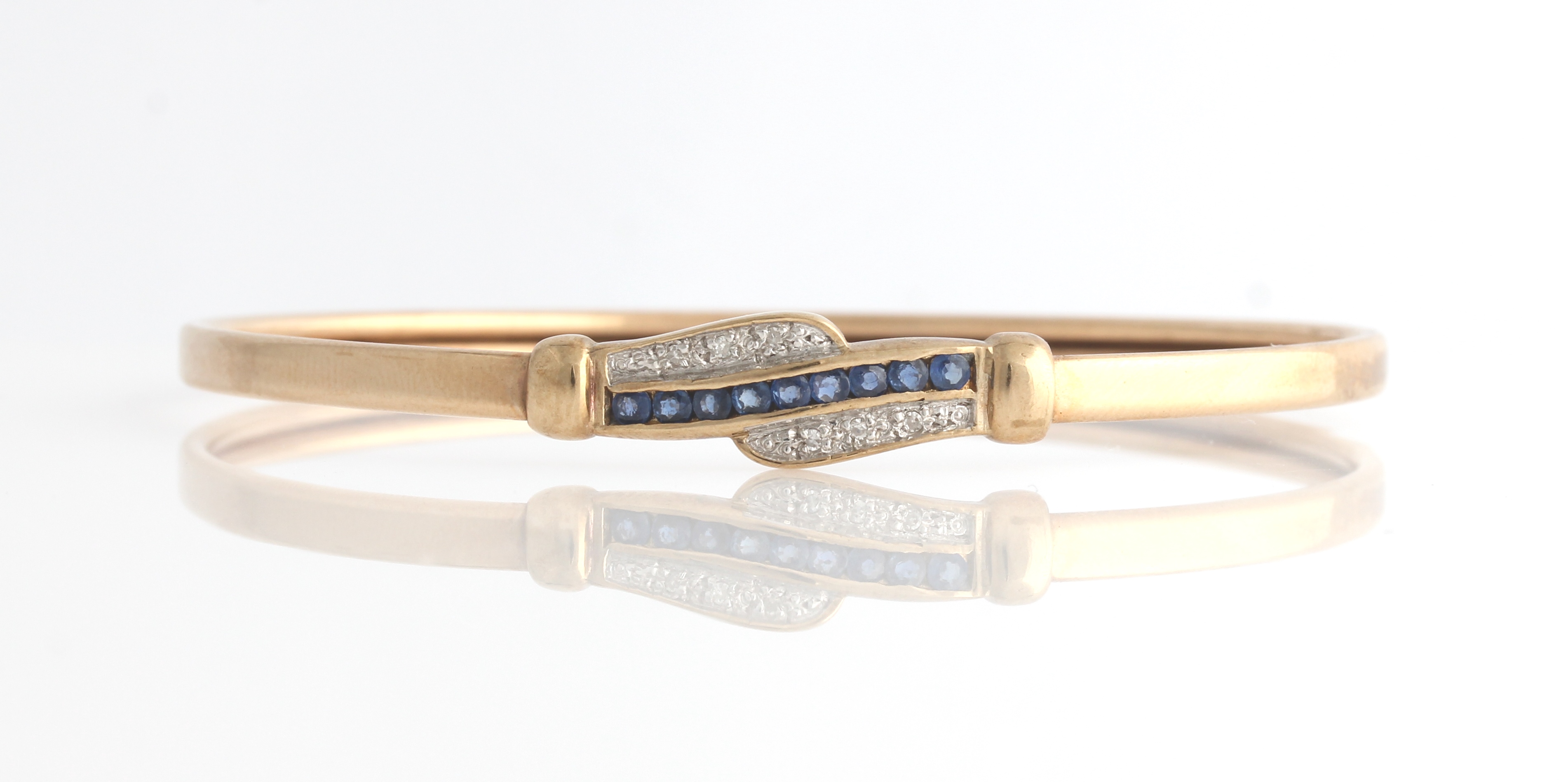 A sapphire and diamond bangle, stone set section featuring a central row of round cut sapphires