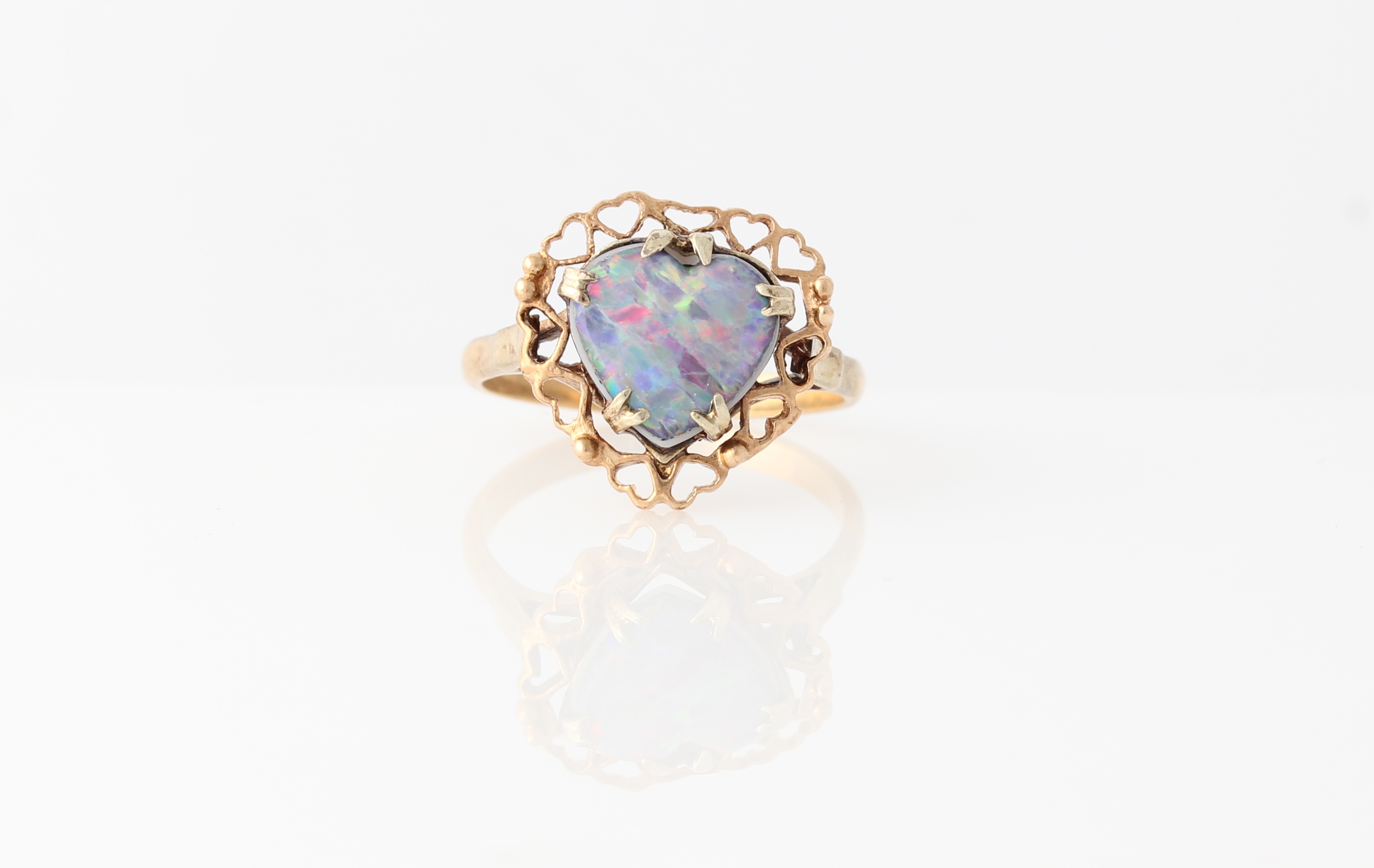 An opal triplet ring, set with a heart shaped opal triplet, surrounded by a border of open heart