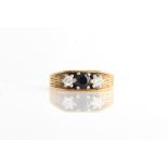 An 18ct yellow gold, sapphire and diamond three stone ring, set with a central round cut sapphire,