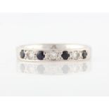 A hallmarked 18ct white gold half eternity ring, set with three diamonds and four sapphires,