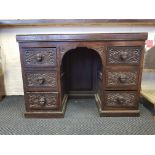 A carved oak knee hole writing desk with carved head handles.