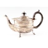 An early 20th century hallmarked silver teapot with hoofed feet stands and a wooden handle.