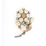 A gemstone set flower design brooch, set with yellow and blue stones in unmarked white metal.