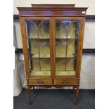 A late Victorian inlaid mahogany glazed two door display cabinet, fitted two drawers on square