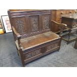 A carved oak hall bench with storage seat.