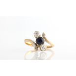 A sapphire and diamond ring, set with a central round cut sapphire and two old cut diamonds, each