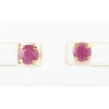 A pair of ruby stud earrings, each set with a round cut ruby, stamped 10k.