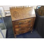 A burr walnut fall front writing bureau with fitted interior, and four long drawers below on claw