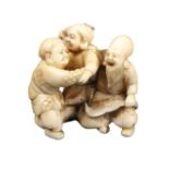 A 19th Century Japanese carved ivory netsuke of three male figures, two wrestling, the other a
