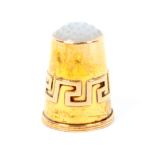 A continental gold thimble the plain sides with a Grecian Key band below a polished stone top