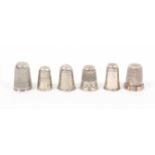 Six silver thimbles, two of tall form with plain sides, and four others one with frieze in raised