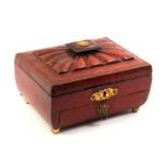 A Regency red leather covered sewing box of sarcophagal form, on four gilt brass ball feet and