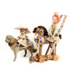 Two porcelain headed dolls each on a horse, the first on a ribbon decorated wheeled wooden horse,