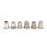 Six continental white metal early 20th Century thimbles five with stone tops, two with engraved