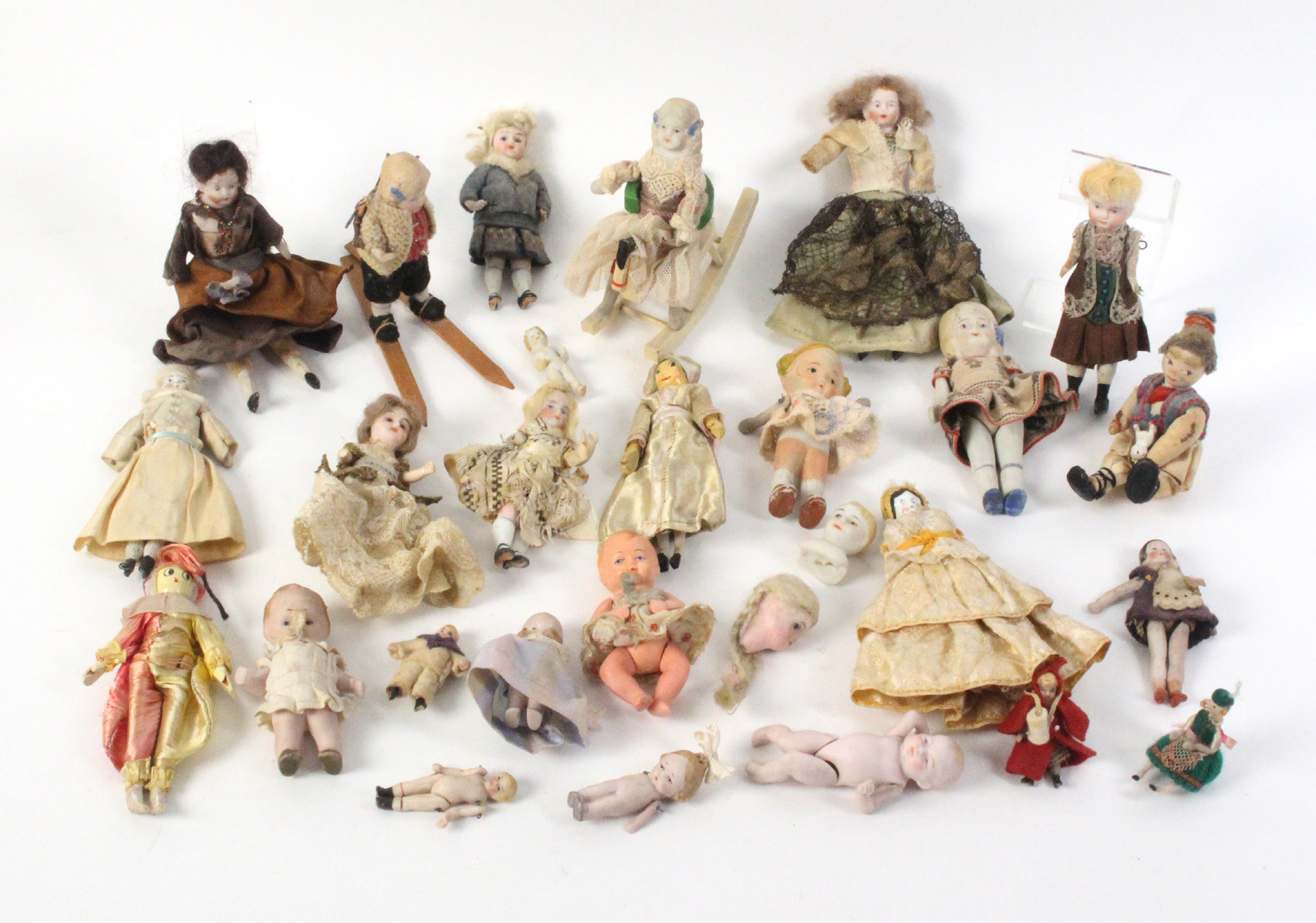 Twenty-two Victorian and later small format dolls mostly ceramic, two ceramic heads, a doll on skis,