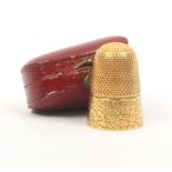 A 19th Century gold thimble the frieze with a punched sponge work design, in associated red