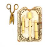 A rare card of miniature bone sewing accessories for a doll, the card with gilt printed border and