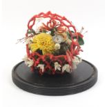 A Victorian group of wax flowers contained in a wax coral form basket, losses, 21cm dia., 21cm high
