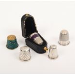 Five thimbles comprising a silver thimble with purple enamel band in leather case, and four others