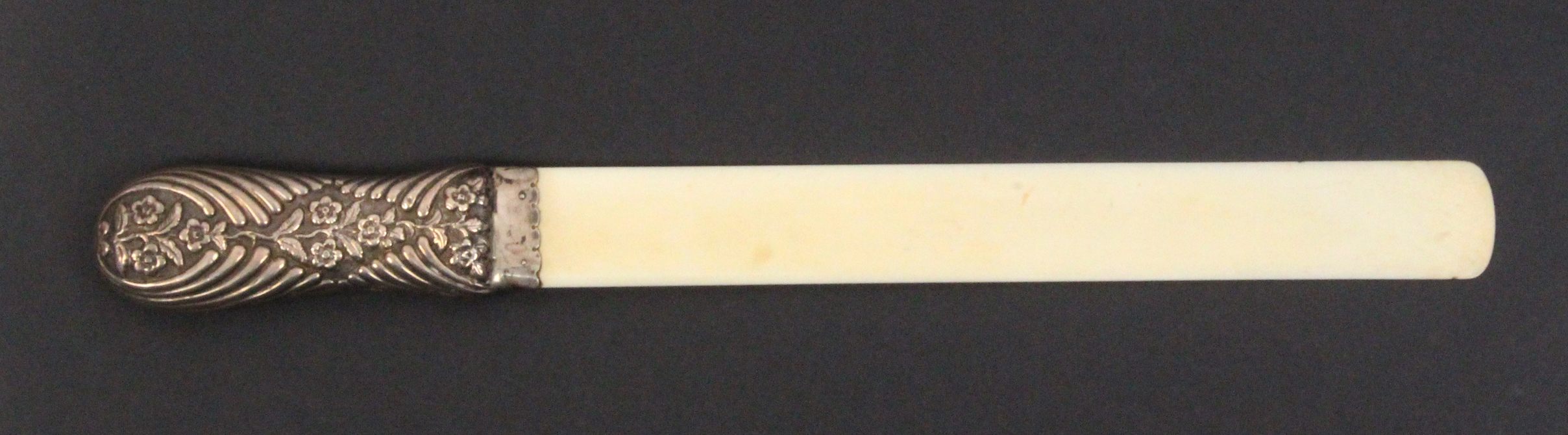 An ivory silver handled page turner, the handle decorated with flowers, London, marks rubbed, 40cm