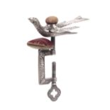 A white metal hemming bird sewing clamp, rectangular leaf decorated frame below a pin cushion, the