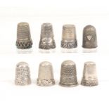 Eight continental white metal thimbles all with decorative borders, one with applied shield (8)