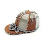 A good jockey cap pin cushion in alternate silk and corded panels with corded peak, pin stuck