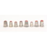 Eight continental white metal early 20th Century thimbles all with coloured stone tops, three with