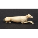 A finely carved 19th Century ivory needle case in the form of a dog lying at rest, front paws