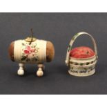 Two painted bone pin cushions comprising a basket form circular example painted with flowers and