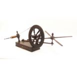 An early 19th Century oak bobbin winder with spindle turned wheel, swing arm with cross form