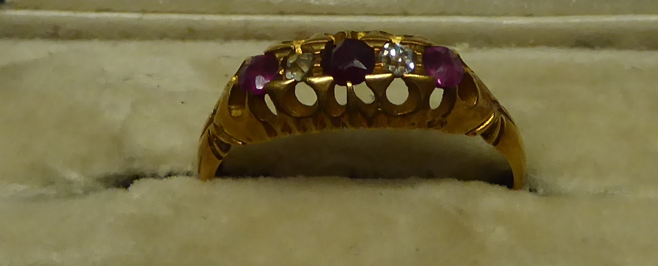 A late Victorian 18ct gold Ring with three rubies and two diamonds in an open work setting,