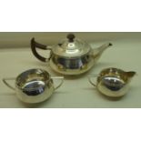 A silver circular three piece Teaset of compressed form, the teapot with stained wood handle and