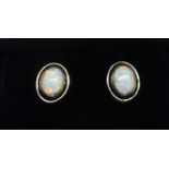 A pair of silver oval Earrings each set with a single opal.
