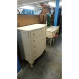 A cream bow front chest of drawers and a dressing table