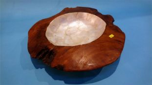 A carved wooden bowl with mother of pearl centre.