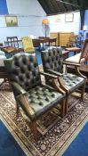 A pair of green buttoned back leather Chesterfield carver chairs