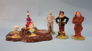 Three Beswick Flintstone figures, three Royal Doulton Wizard of Oz figures and a stand.