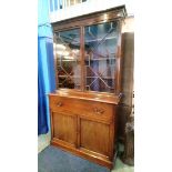 A mahogany bookcase with glazed top below one long drawer and two cupboard doors, supported on a