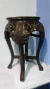 An Oriental carved hardwood table with inset marble to the top and carved legs, 30cm diameter (max)