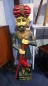 A decorative painted and carved wood model of an Indian gentleman holding a staff, 121cm height