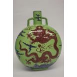 A Chinese Moon flask on an apple green ground, decorated with red five clawed dragon above a