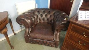 A brown leather Chesterfield armchair