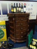 A carved oak demi lune chest of drawers, with mirrored top, below five short drawers. 81cm wide