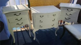 A cream bow front chest of drawers and a pair of bedside drawers