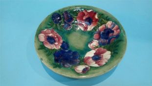 A Moorcroft shallow bowl on a green ground, decorated with flowers, impressed mark and signed,