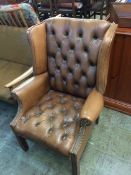 A brown Chesterfield wing armchair